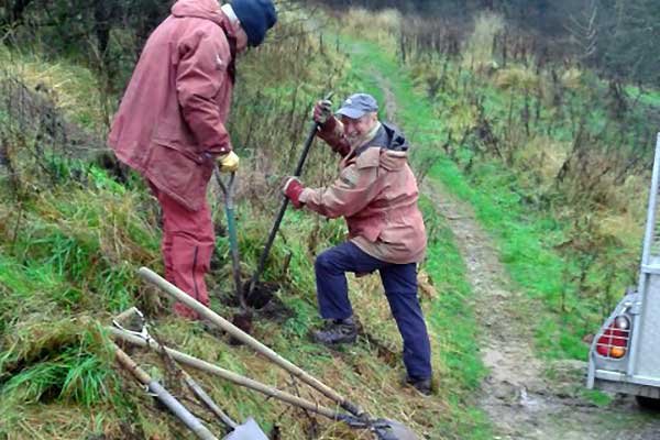 Two volunteers using a variety of digging tools