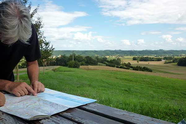 Someone looking at a map with a flat summer landscape beyond