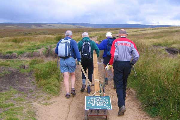 Four members of the signpost team taking a sign to its installation location